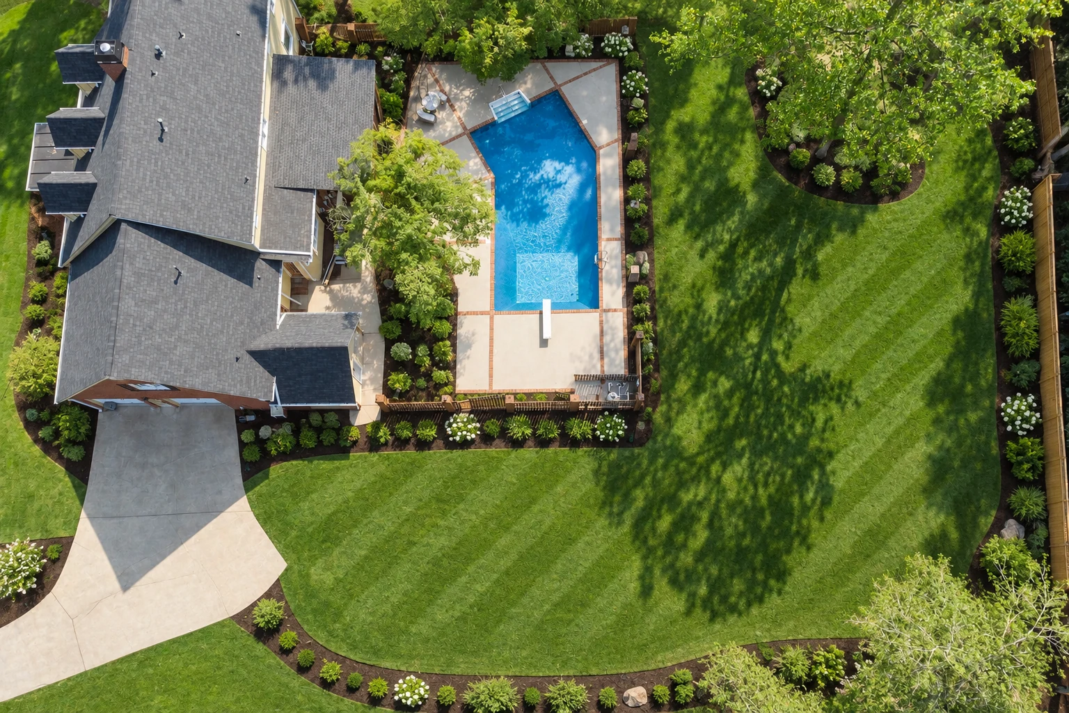 After: the same backyard finished with striped sod, mulched beds and shrub borders