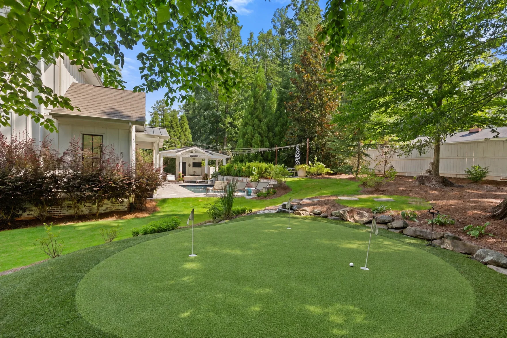 Backyard putting green framed by lawn and trees
