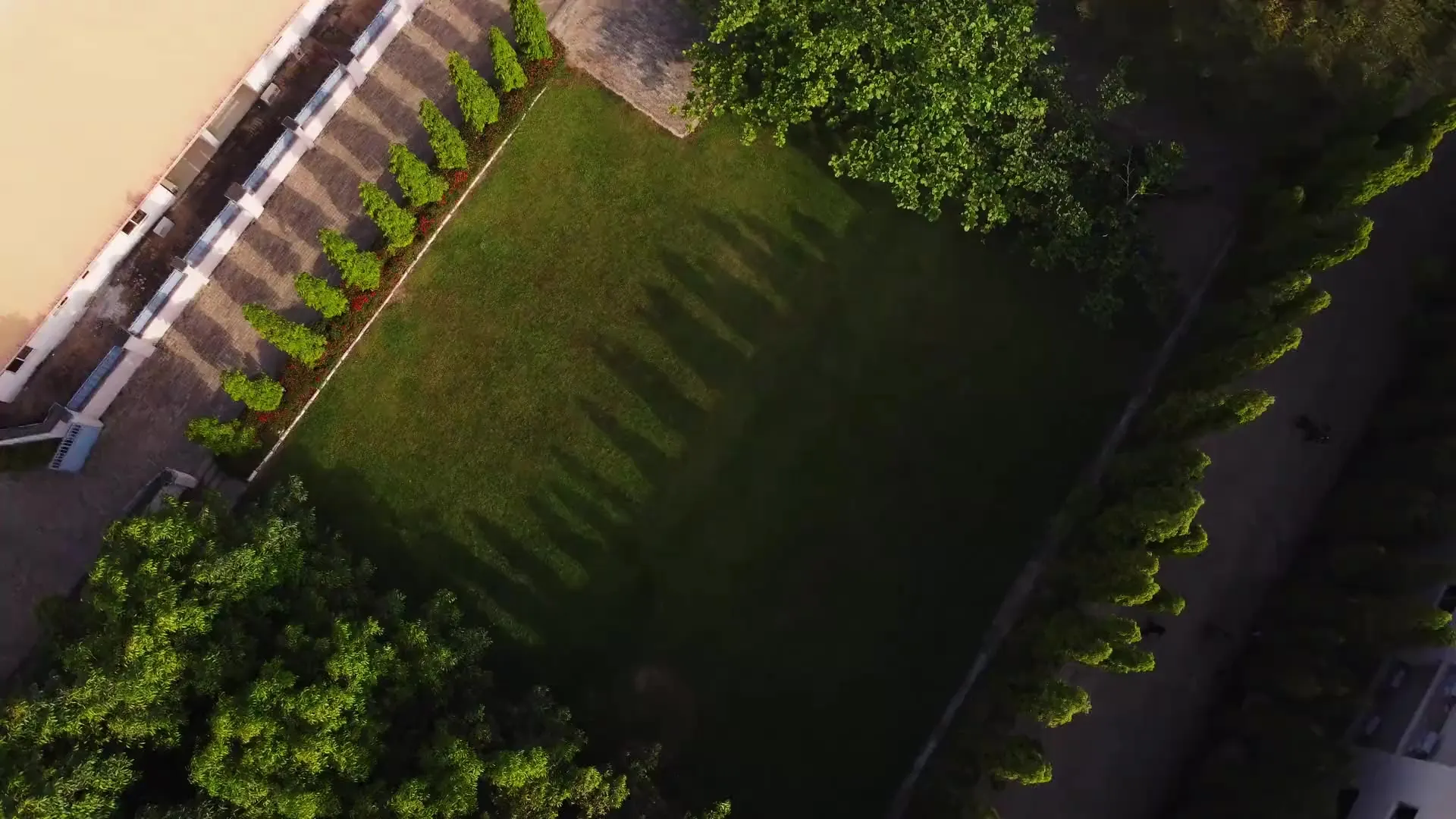 Aerial view of a green lawn framed by trees and clipped evergreens